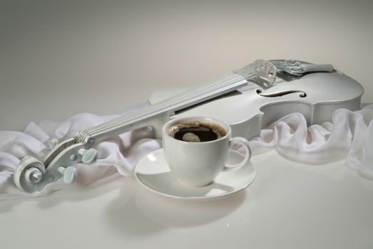 White violin and cup of coffee on a glass background