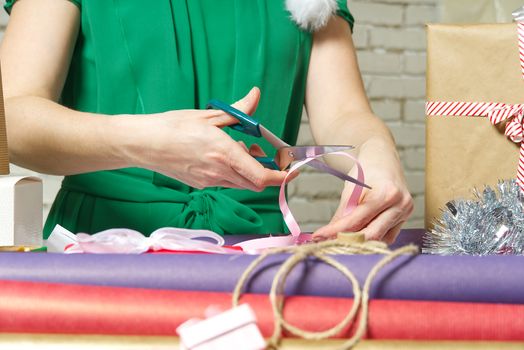 Woman wrapping christmas presents to violet packing paper. woman hands packing a christmas gift, diy gift packing and wrapping concept.