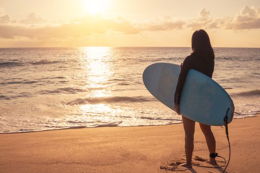 Silhouette of surfer woman carrying their surfboards on sunset beach with sun light  background