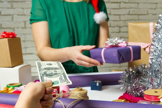 Paying for Gift Wrap at wrapping and packing service table with USA dollars banknotes.