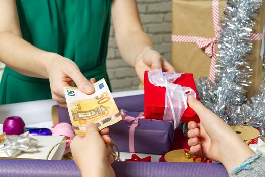 Paying for Gift Wrap at wrapping and packing service table with Euro banknotes.