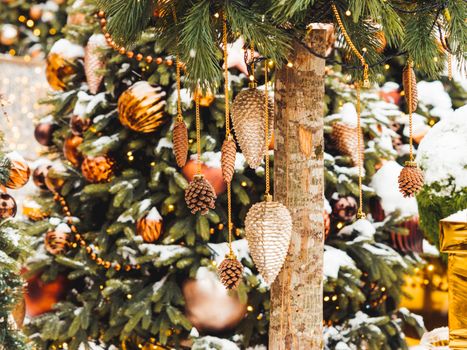 Christmas tree with golden and bronze decorations. Outdoor decorative pine cones and balls for New Year celebration.