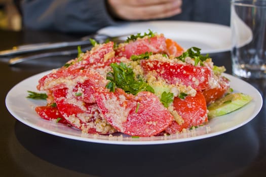 Georgian salad with tomatoes, cucumber, greens and walnut souse, close-up