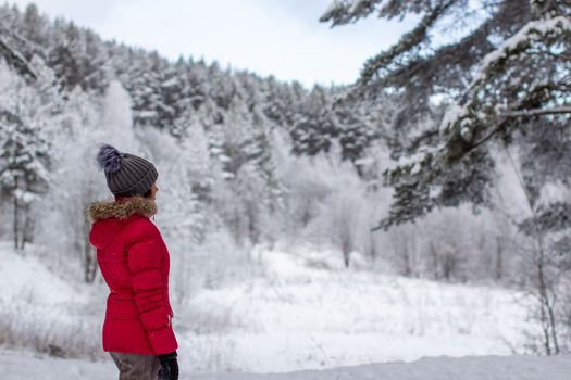 A young woman in a red jacket in a winter forest. Winter and frosty forest in the mountains. Nature walk