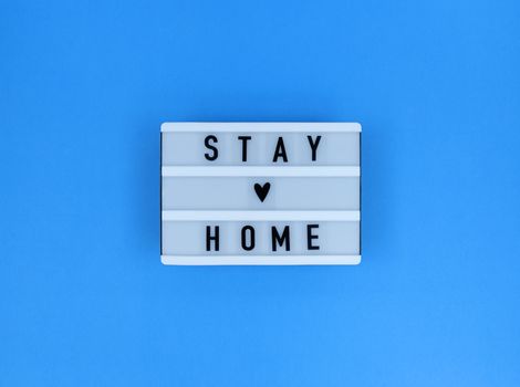 Light box with Stay home quote on blue background.