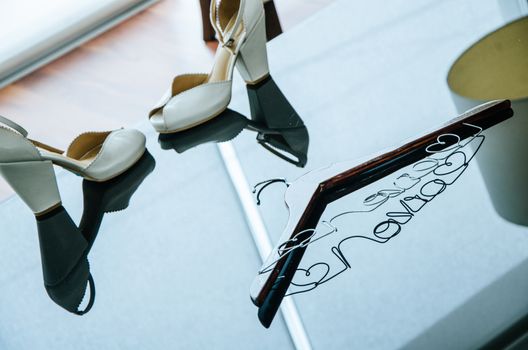 Wedding brides. Shoes of the bride, a hanger for the dress of a bride, perfume.