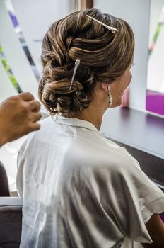 Beautiful, girl with long hair, hairdresser weaves a French braid, in a beauty salon. Creating hairstyles.