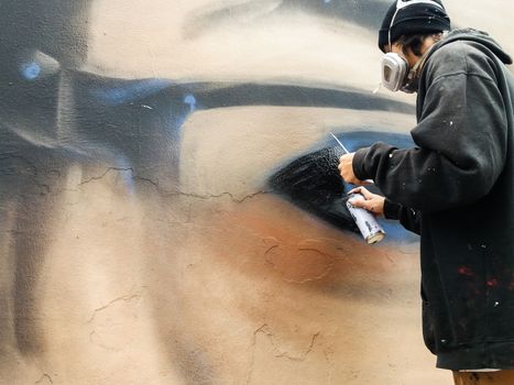 Young urban painter starting to draw graffiti on the wall