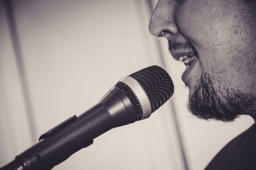 Close-up face of the singer with microphone and singing on black and white background , musical concept