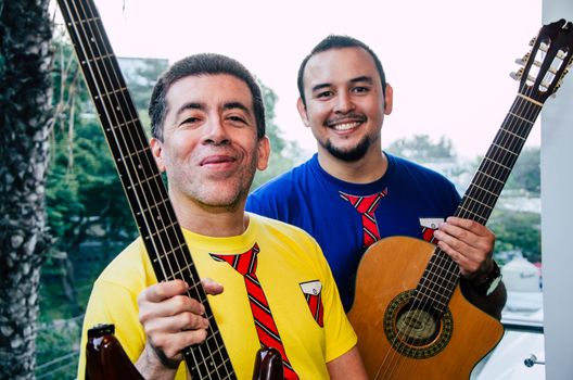 Young smiling people playing guitars with natural background