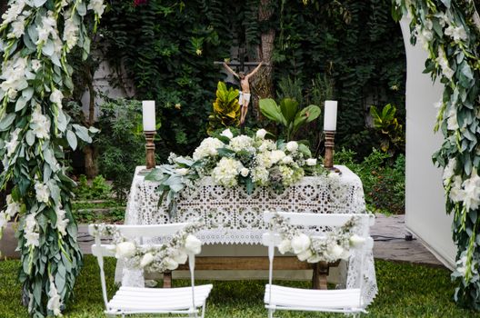 White pillars with bouquets of roses surround place prepared for wedding ceremony