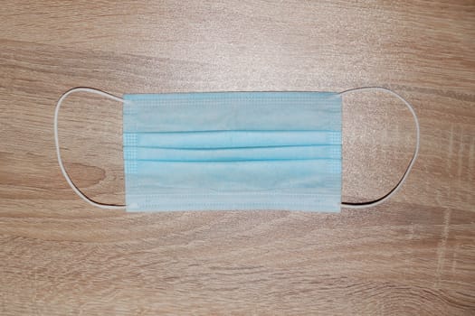 medical protective mask on a light wooden background close-up