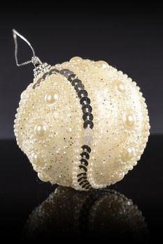 A closeup vertical composition of a white festive holiday bauble for tree decorating during the Christmas season.