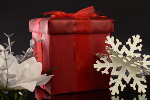 A closeup image of a red Christmas gift with decorative items to compliament the festive season.