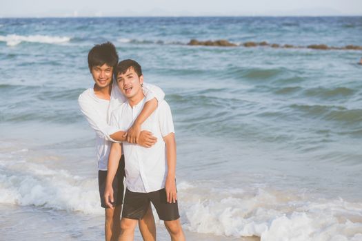 Homosexual portrait young asian couple standing hug together on beach in summer, asia gay going tourism for leisure and relax with romantic and happiness in vacation at sea, LGBT concept.