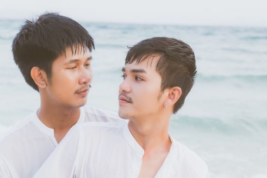 Homosexual portrait young asian couple standing hug and look together on beach in summer, asia gay going tourism for leisure and relax with romantic and happy in vacation at sea, LGBT legal concept.
