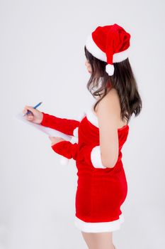 Beautiful portrait young asian woman writing notepad in xmas day isolated on white background, beauty asia girl writing list shopping or wish with excited for celebrating in Christmas holiday.