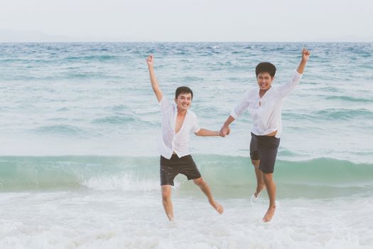 Homosexual portrait young asian couple running and jump with cheerful together on beach in summer, asia gay going tourism for leisure and relax with happiness in vacation at sea, LGBT legal concept.