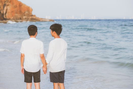 Back view homosexual portrait young asian couple walking with cheerful together on beach in summer, asia gay going tourism for leisure and relax with happiness in vacation at sea, LGBT legal concept.