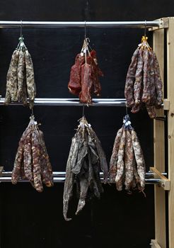 Close up selection of smoked and cured meat sausages hanging on retail display, low angle view