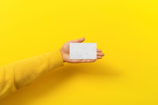 piece of paper in the female hand over yellow trendy background, empty blank for advertisement