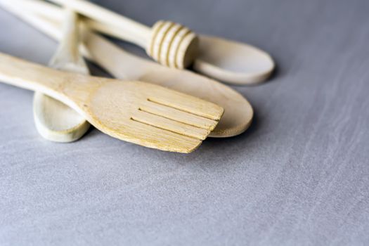 Group of wooden kitchen utensils arranged on a gray marble table. Selective focus on the carving fork.