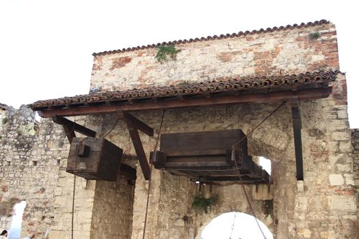 Stone wall with merlons and drawbridge gate of medieval castle of Brescia in north Italy