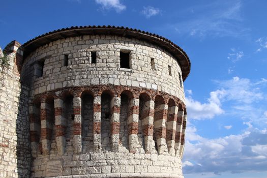 Stone wall with merlons and drawbridge gate of medieval castle of Brescia in north Italy