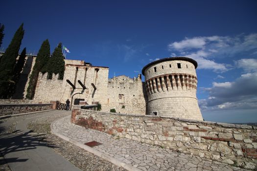 Stone wall with merlons and drawbridge gate of medieval castle of Brescia in north Italy