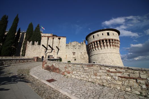 Stone wall with merlons and drawbridge gate of medieval castle of Brescia in north Italy