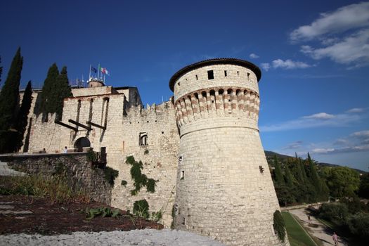 Stone wall with merlons and drawbridge gate of medieval castle of Brescia in north Italy