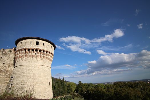 Stone wall with merlons and drawbridge gate of medieval castle of Brescia in north Italy