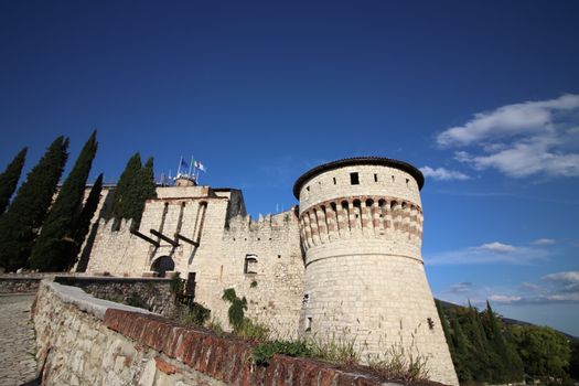 Stone wall with merlons and drawbridge gate of medieval castle of Brescia in north Italy