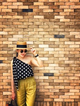 Portrait of young beautiful woman wearing a planter panama hat with brick wall background