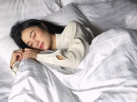 Beautiful asian woman sleeping in bed under white quilt with head on pillow comfortable and happy. girl with relax for health concept.