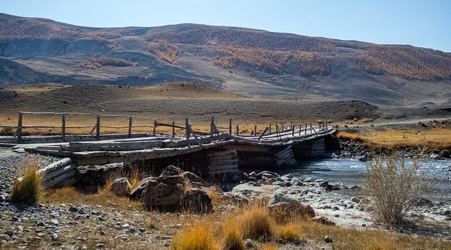 An old wooden bridge over a mountain river in the Altai.