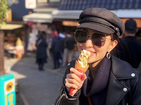 Young tourist woman eating ice cream cone covered with real gold leaf a famous street food in Japan