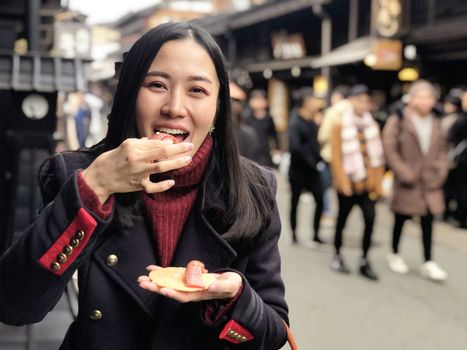 Young woman tourist enjoy eating Japanese street food Hida Beef Sushi and cracker at Takayama, Japan