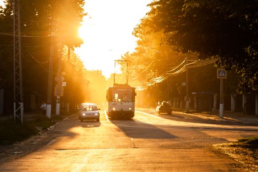 TULA, RUSSIA - JUNE 6, 2013: Car and tram on traffic light stop under golden sun backlight, Dust in the air volumetric glowing bright.