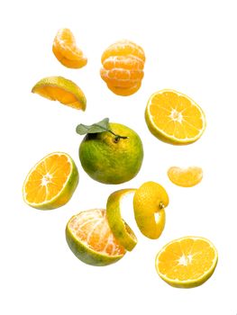 Fresh ripe green mandarine with leaf falling in air. Cut, peeled, slices and whole green tangerine isolated on white background with clipping path. Food levitation concept