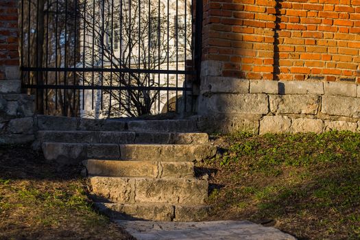 stairs to wicket in white mansion's brick fence in sundown evening, view with selective focus