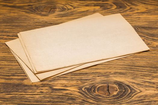 sheets of old yellow paper on wooden table surface with selective focus
