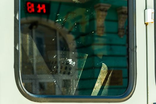 Police shields inside van window with green architecture and public red digital clock reflection 