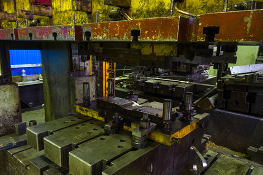 old dirty big yellow-green mechanical press with plate and stamp inside, selective focus