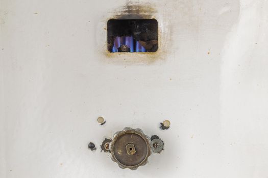 Fired up old russian gas water heater with flat front panel closeup