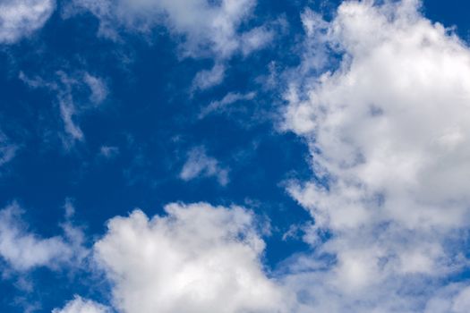 white c cumulus clouds on blue sky background telephoto view