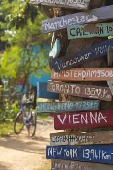 Colourful hand painted direction wood signs to different cities of the world, and mileage marker in Don Det island, one of the famous Four Thousand Islands or Si Phan Don, in the Mekong river, Laos.