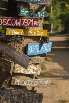 Colourful hand painted direction wood signs to different cities of the world, and mileage marker in Don Det island, one of the famous Four Thousand Islands or Si Phan Don, in the Mekong river, Laos.