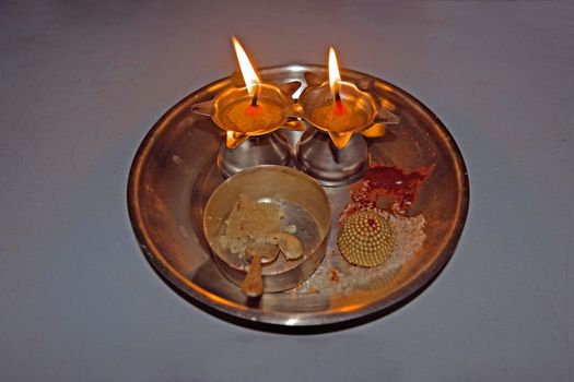 Isolated image of Indian Puja thali with two lit lamps.