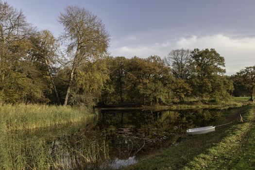 two boats in a pond in the autum forest with red brown and golden colors in national park de veluwe in holland